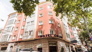A multi-story hotel with a curved facade, a prominent "HOTEL COLON" sign, and a ground-level entrance. - Hotel Amic Colón (Palma de Mallorca)