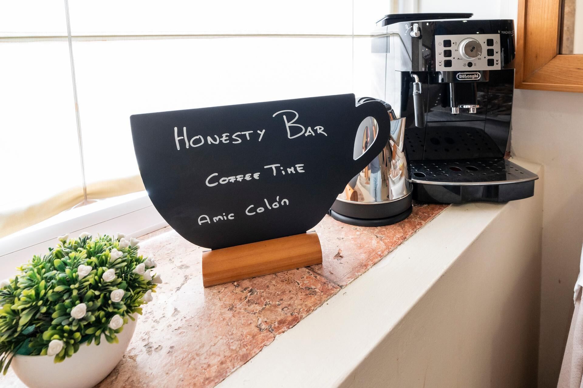 A coffee machine, a sign reading "Honesty Bar Coffee Time," and a small potted plant on a counter.