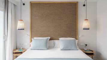 Una habitación de hotel con una cama grande, dos mesitas de noche, una lámpara de pared y una ventana con cortinas.
