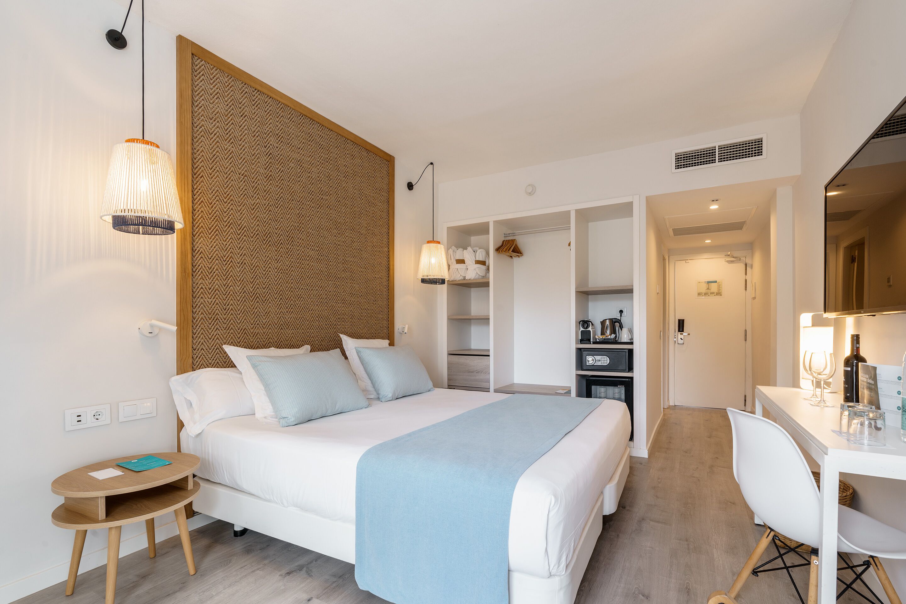 A modern bedroom with a bed, bedside tables, a desk, and a wardrobe.