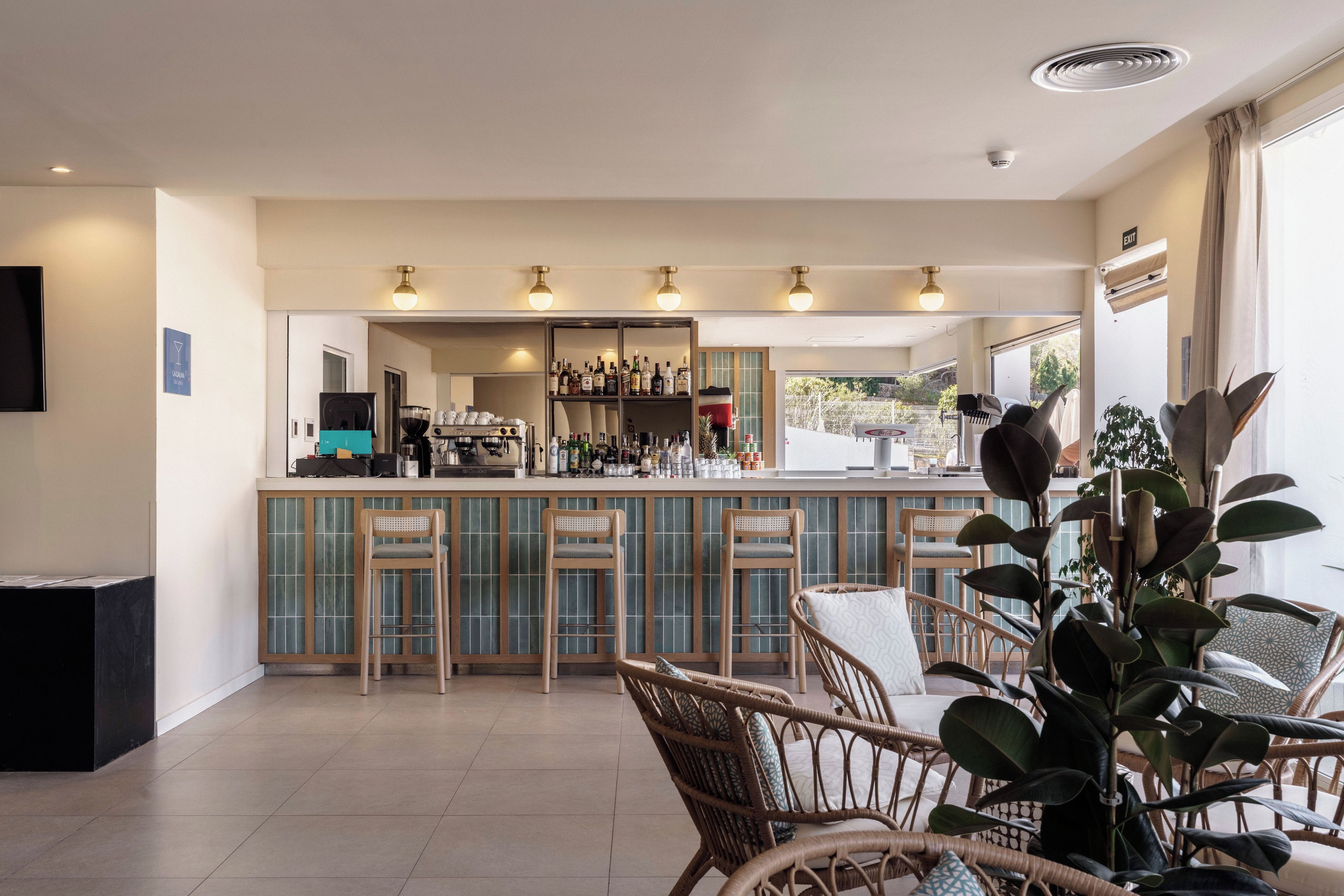 A bar area with seating, a coffee machine, and a variety of bottles.