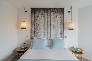 Ein Hotelzimmer mit einem großen Bett, zwei Nachttischen, einem Holzkopfende und Pendelleuchten.