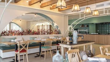 Interior moderno de restaurante con mobiliario de madera, iluminación colgante y salpicadero con azulejos verdes.