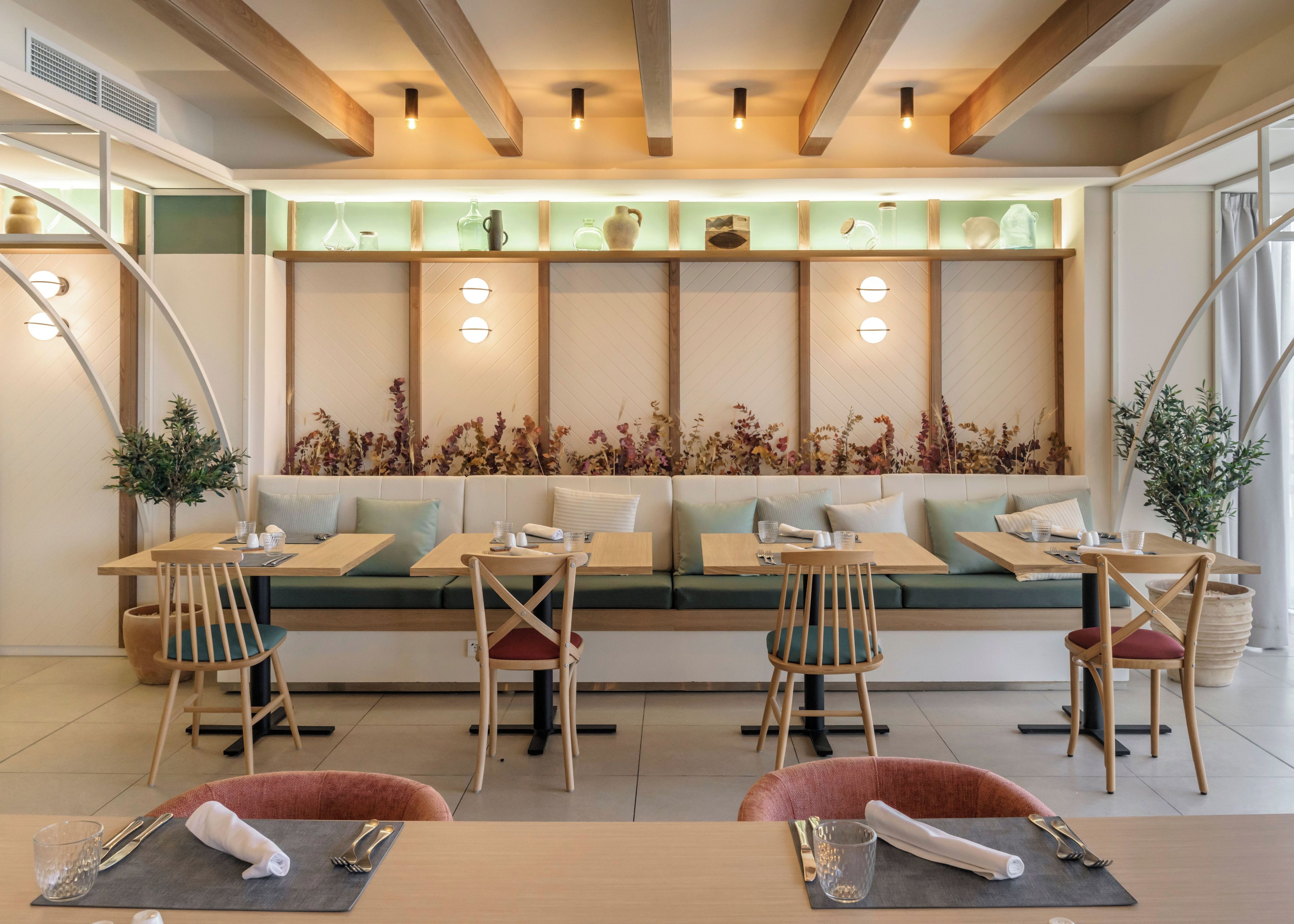Un restaurante con una larga mesa compartida, asientos acolchados y una pared decorativa con luces.