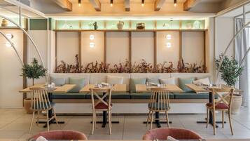 Un restaurante con una larga mesa compartida, asientos acolchados y una pared decorativa con luces.