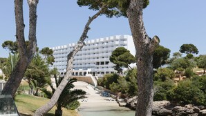 A coastal hotel with a white building, palm trees, and a beach area. - AluaSoul Mallorca Resort - Adults Only (Santanyi)