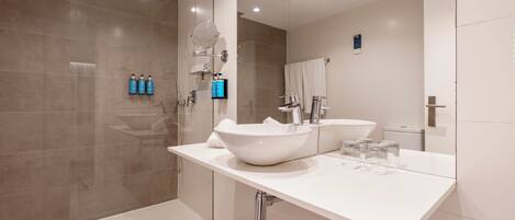 A modern bathroom with a large white sink, a glass shower enclosure, and a mirror above the sink.