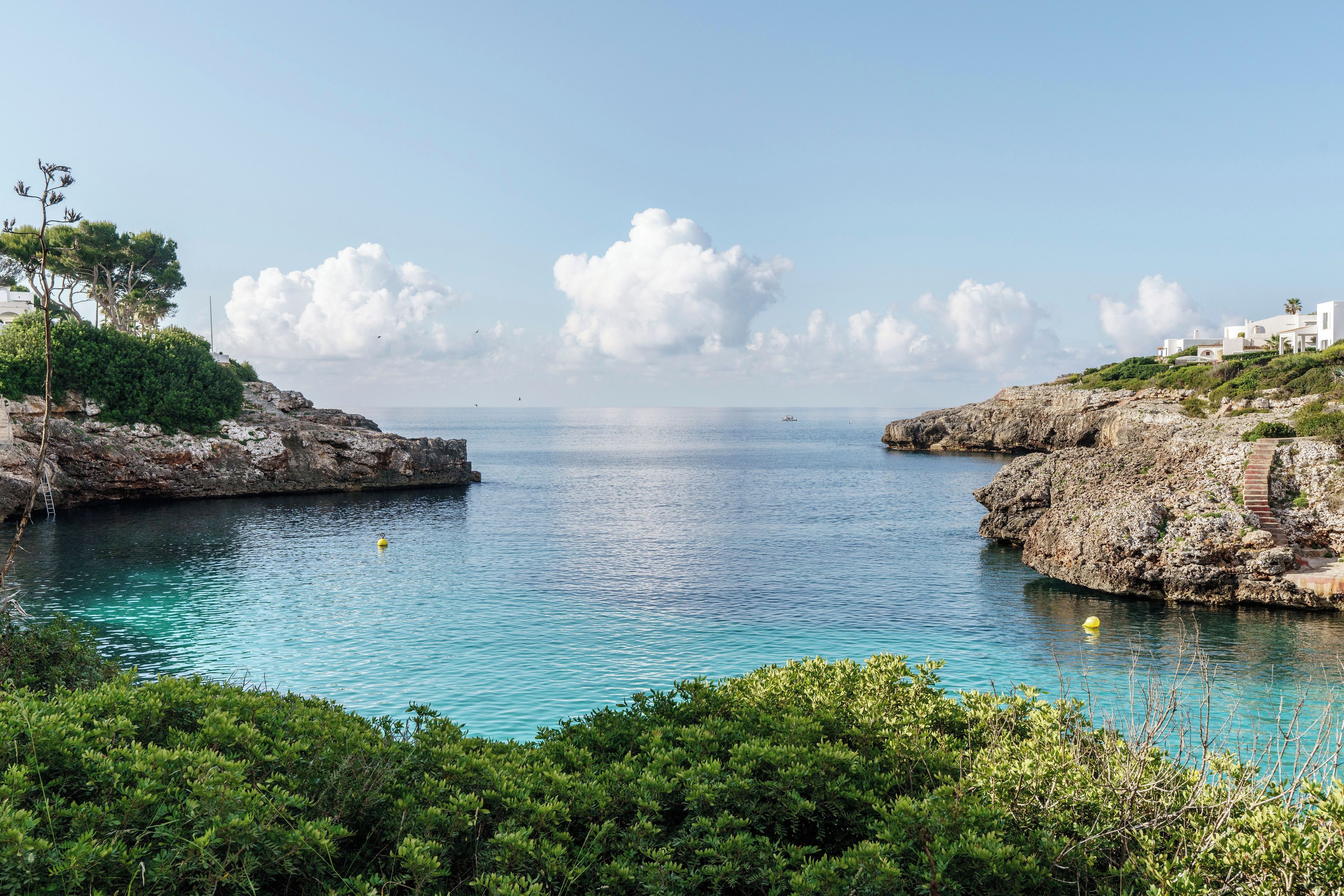 A coastal landscape with rocky terrain, clear blue waters, and lush greenery.