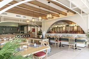 A modern restaurant with a wooden ceiling, pendant lighting, and a cozy seating area with a bench and chairs. - AluaSoul Mallorca Resort - Adults Only (Santanyi)