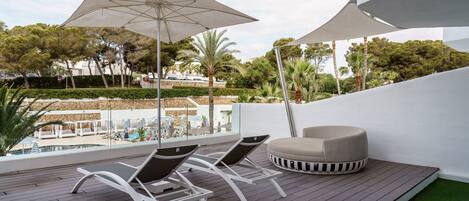 Een terras op het dak met lounge stoelen, een ronde zithoek en parasols voor schaduw.