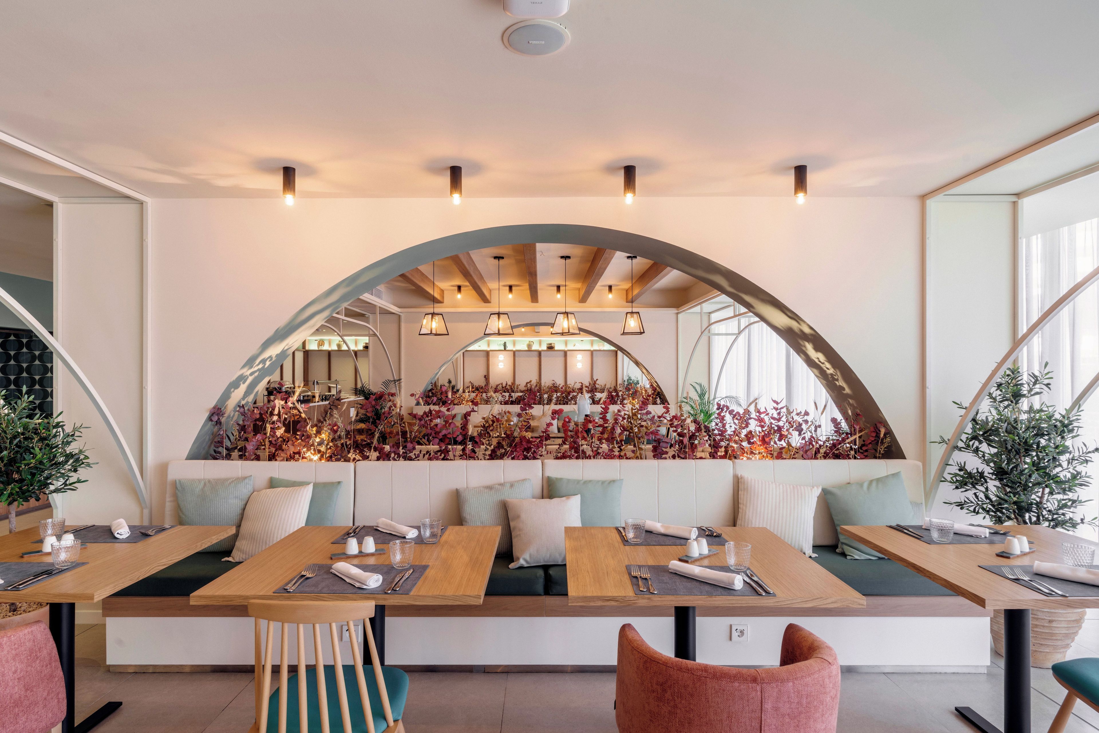 A restaurant with a long communal table, individual seating, and a decorative archway.