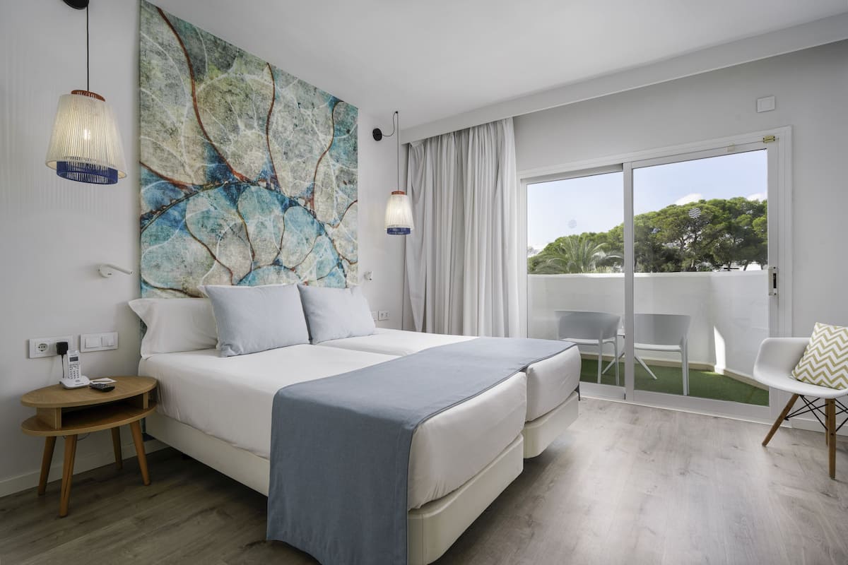 Un dormitorio moderno con una cama grande, vistas al exterior y una mesita con un teléfono.