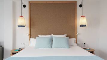 A hotel room with a large bed, two bedside tables, a telephone, and two pendant lights.