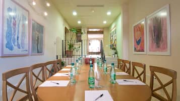Un salón de conferencias con una larga mesa, sillas, botellas de agua y documentos.