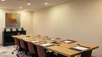A conference room with a long table, chairs, and a cabinet with potted plants.