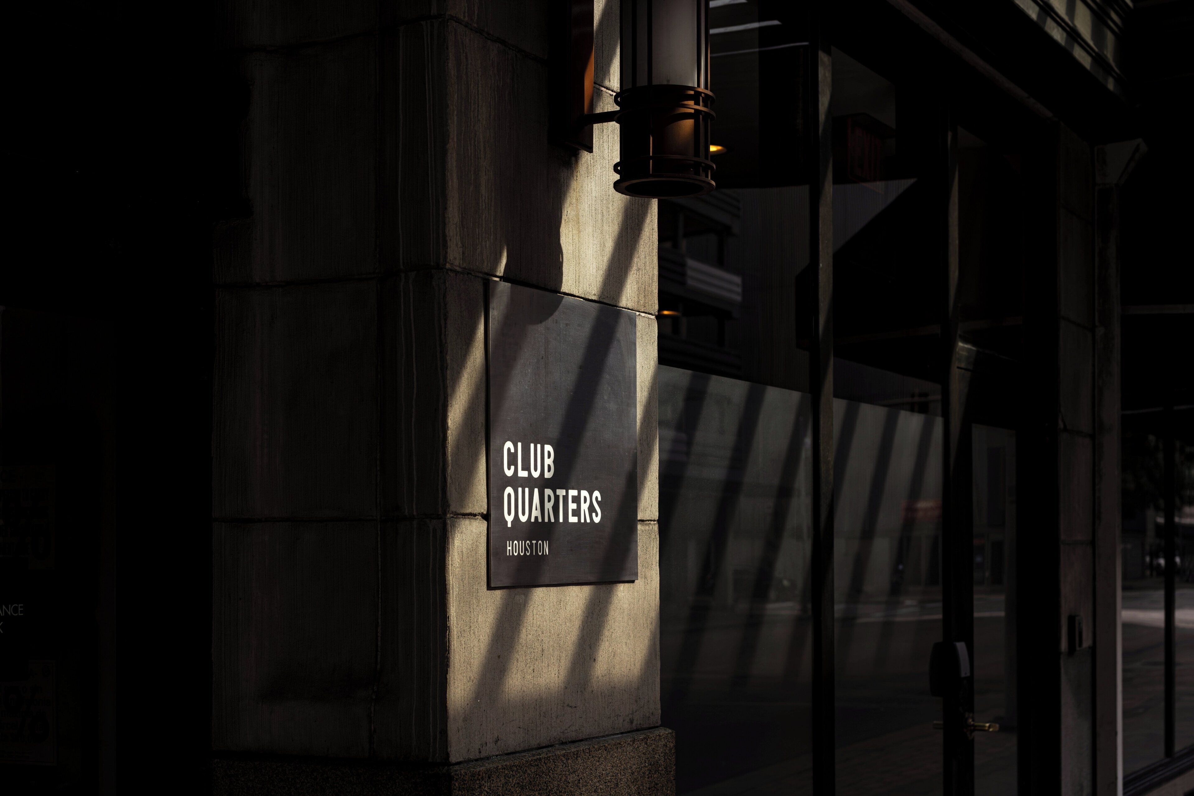 A sign for 'CLUB QUARTERS' on a building facade with a modern design.