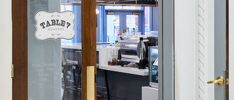 A closed wooden door with a frosted glass panel displaying a sign for 'TABLE7 BISTRO' and a schedule.