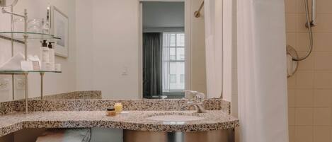 A modern bathroom with a granite countertop sink, a large mirror, and a shower with a curtain.
