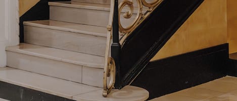 A staircase with ornate golden railings and white steps.