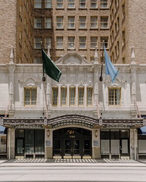 A historic building with a classic facade, ornate architectural details, and two flags.