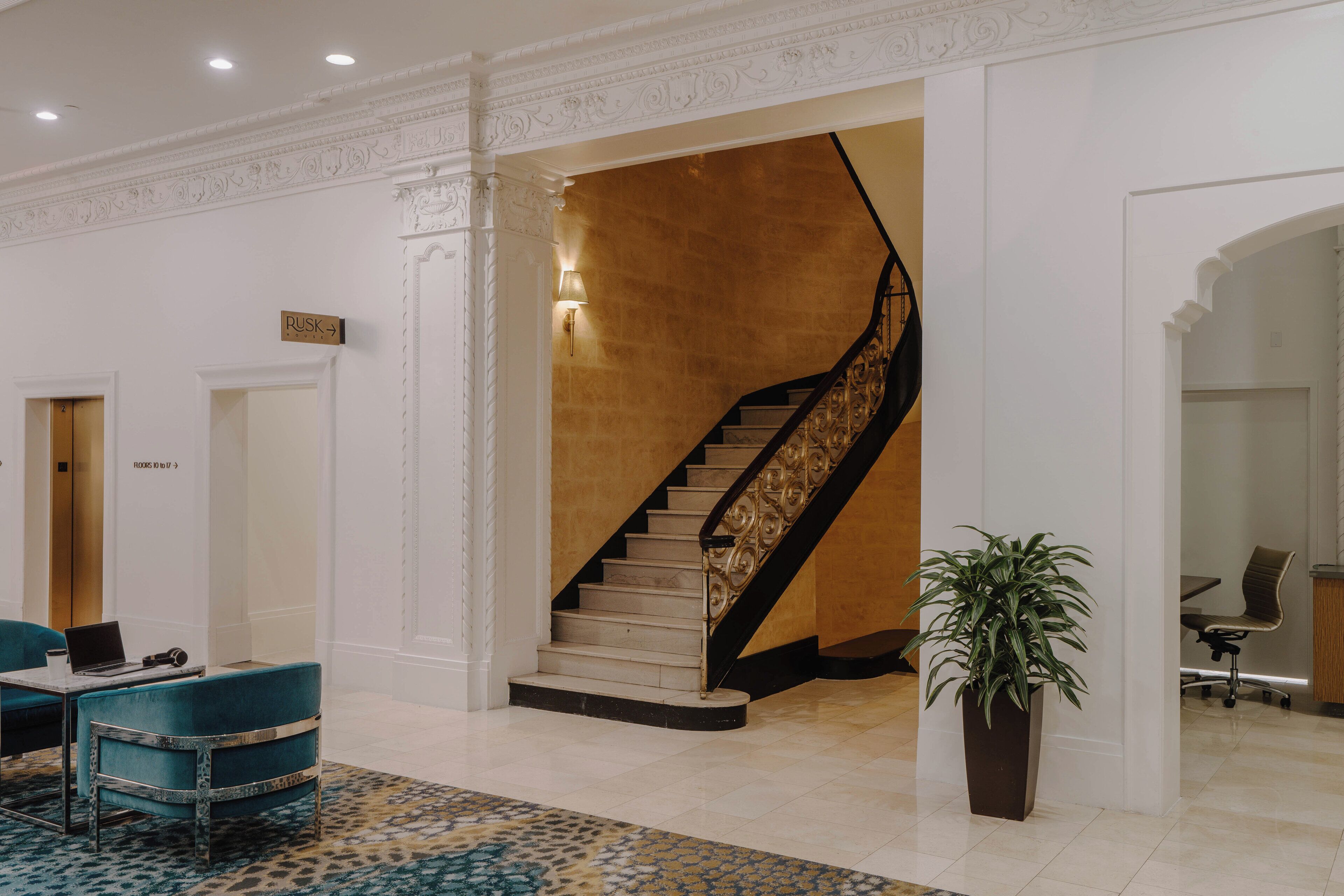 Un hall d’entrée avec un escalier, un comptoir de réception et un espace salon.