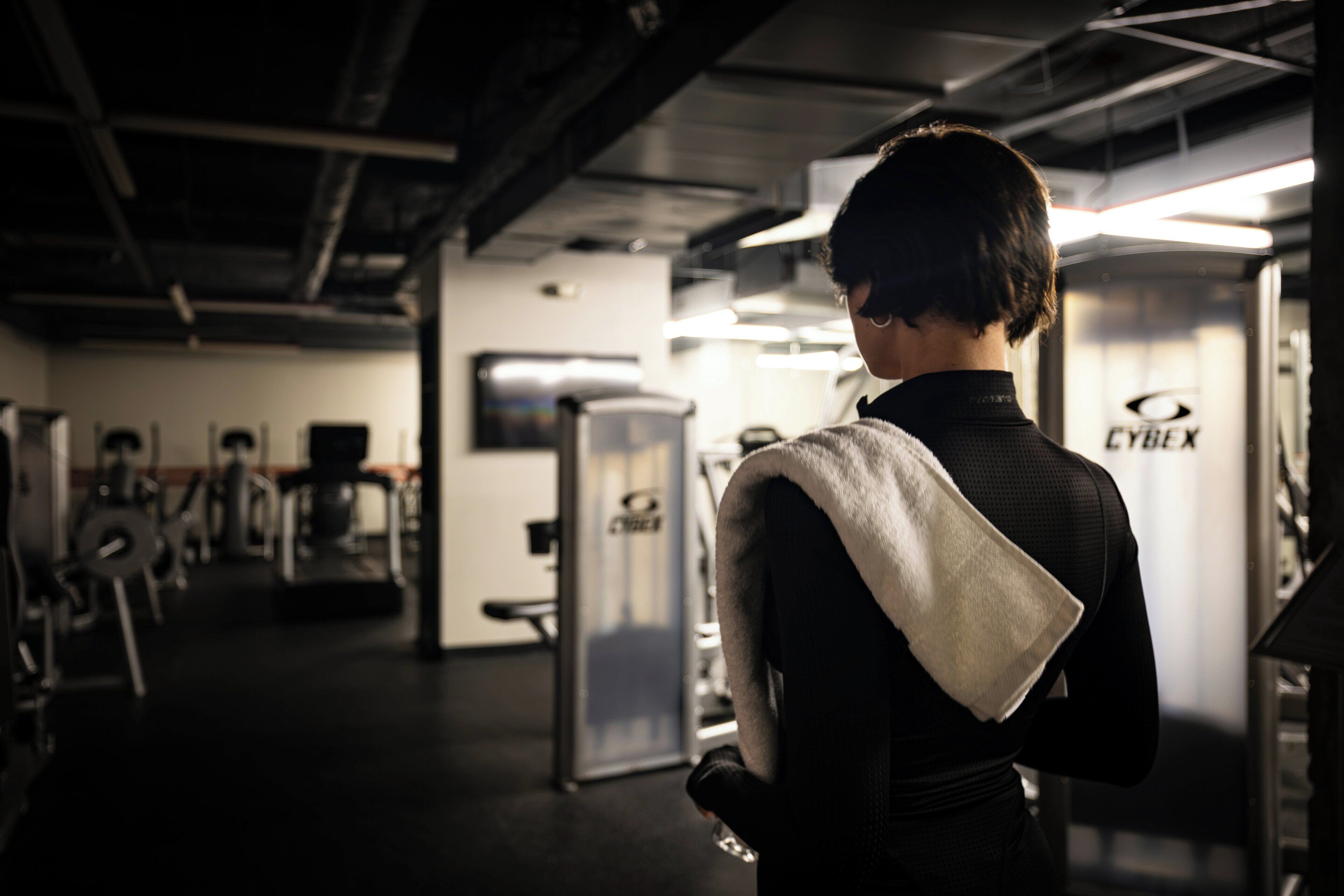 A gym with exercise equipment and a person with a towel.