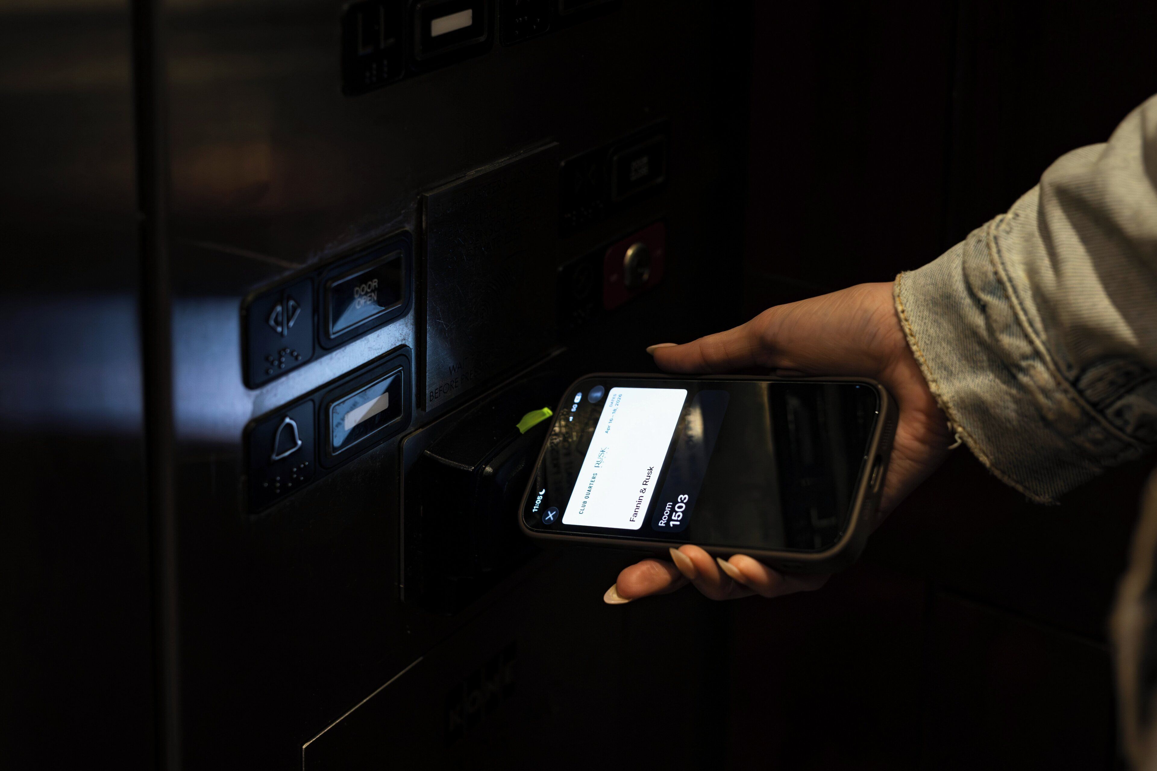 A hand holding a smartphone with a hotel room booking interface.
