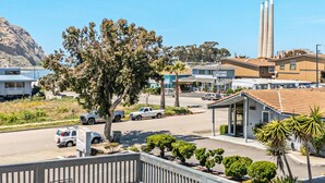 Ein Hotel mit einer Terrasse, Sitzgelegenheiten im Freien und Blick auf die Straße und die umliegenden Gebäude.
