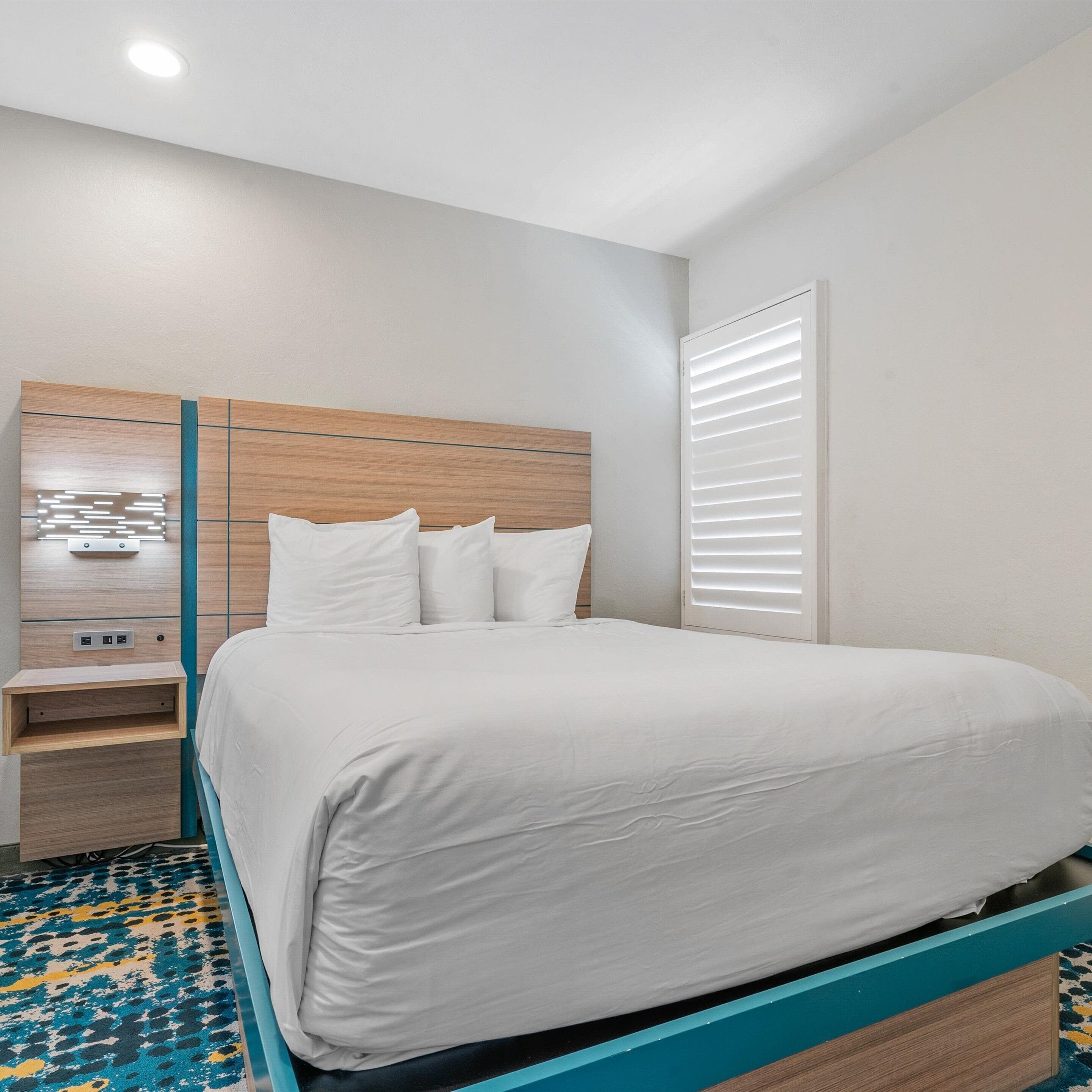 Quarto moderno com cama, mesa de cabeceira e armário embutido.