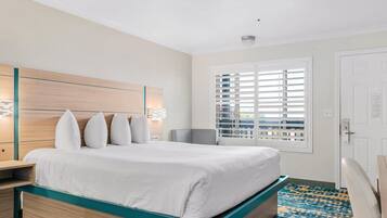 A hotel room with a bed, bedside tables, a window with blinds, and a patterned carpet.