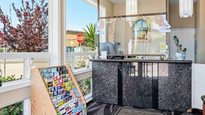 Ein Hotel-Rezeptionsbereich mit einem Holnschild, das verschiedene Reisebroschüren zeigt, einer Marmor-Theke und Blick durch große Fenster nach draußen.
