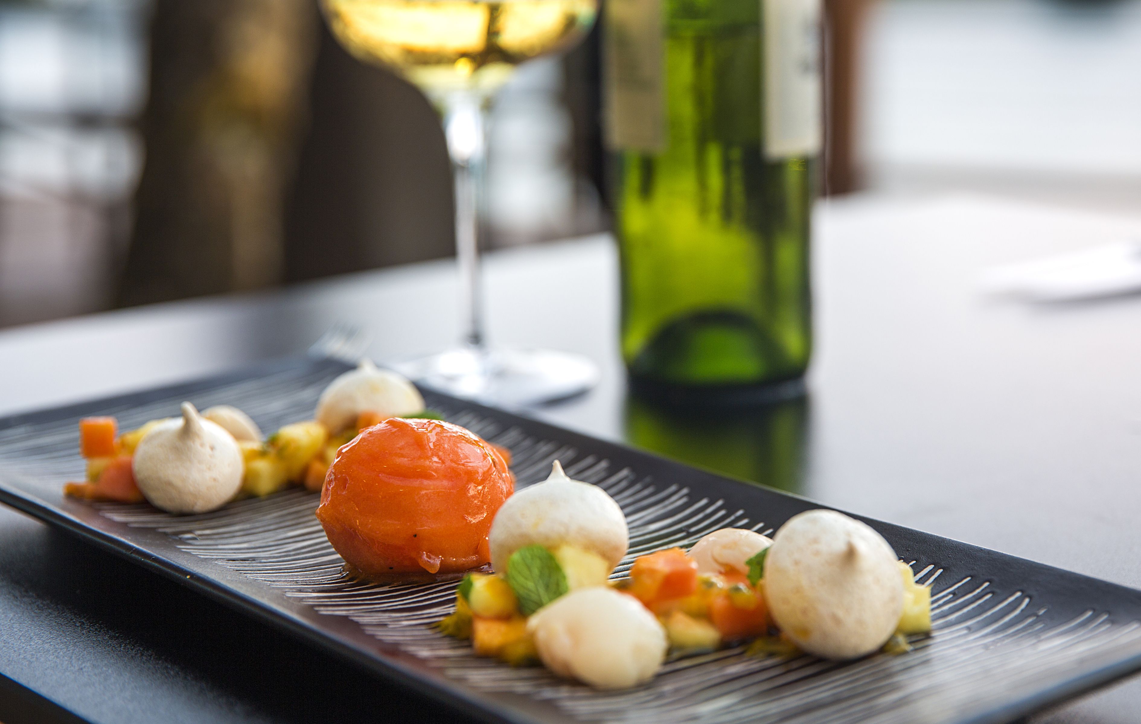 A plate of food with a variety of items including a large orange fruit, small round items, and diced vegetables.