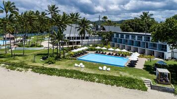 A resort with a swimming pool, lounge chairs, and palm trees.