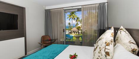 Ein Hotelzimmer mit einem Bett, einem Fernseher, einem Sessel und Blick ins Freie.