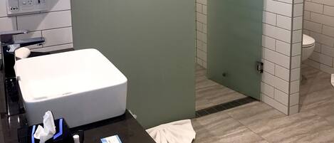 A modern bathroom with a large mirror, a white sink, and a glass-enclosed shower area.