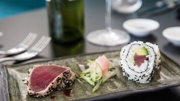 A plate of sushi and a bottle of wine on a table.