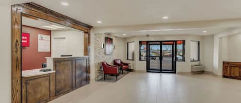 A reception area with a wooden reception desk, a red wall with a Wi-Fi sign, and a stone wall with a sign.