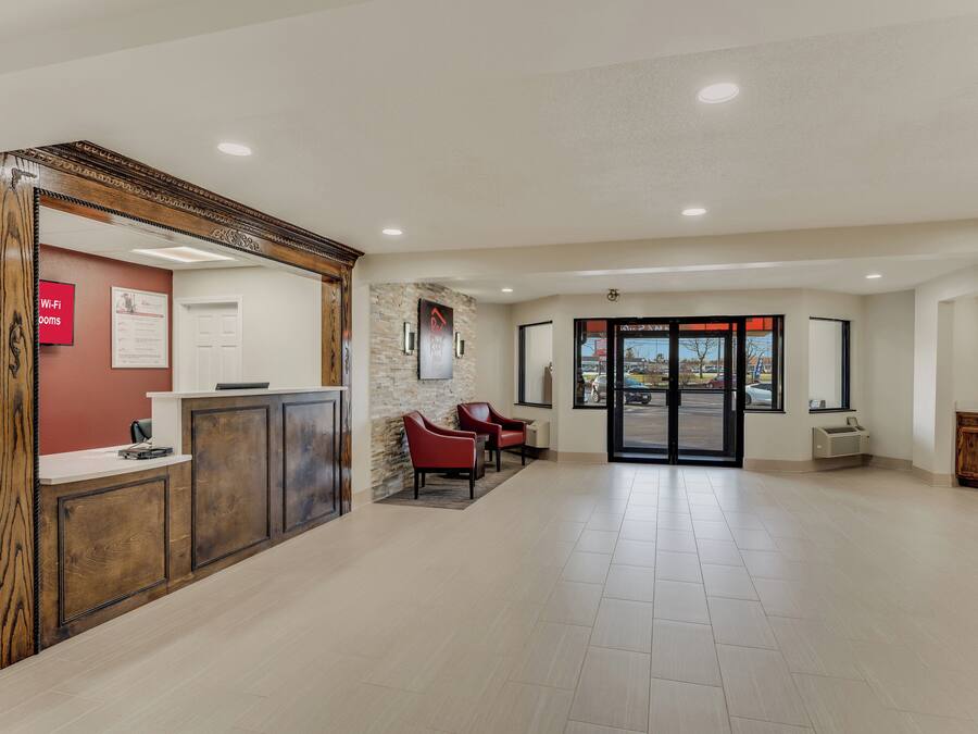 A reception area with a wooden reception desk, a red wall with a Wi-Fi sign, and a stone wall with a sign.