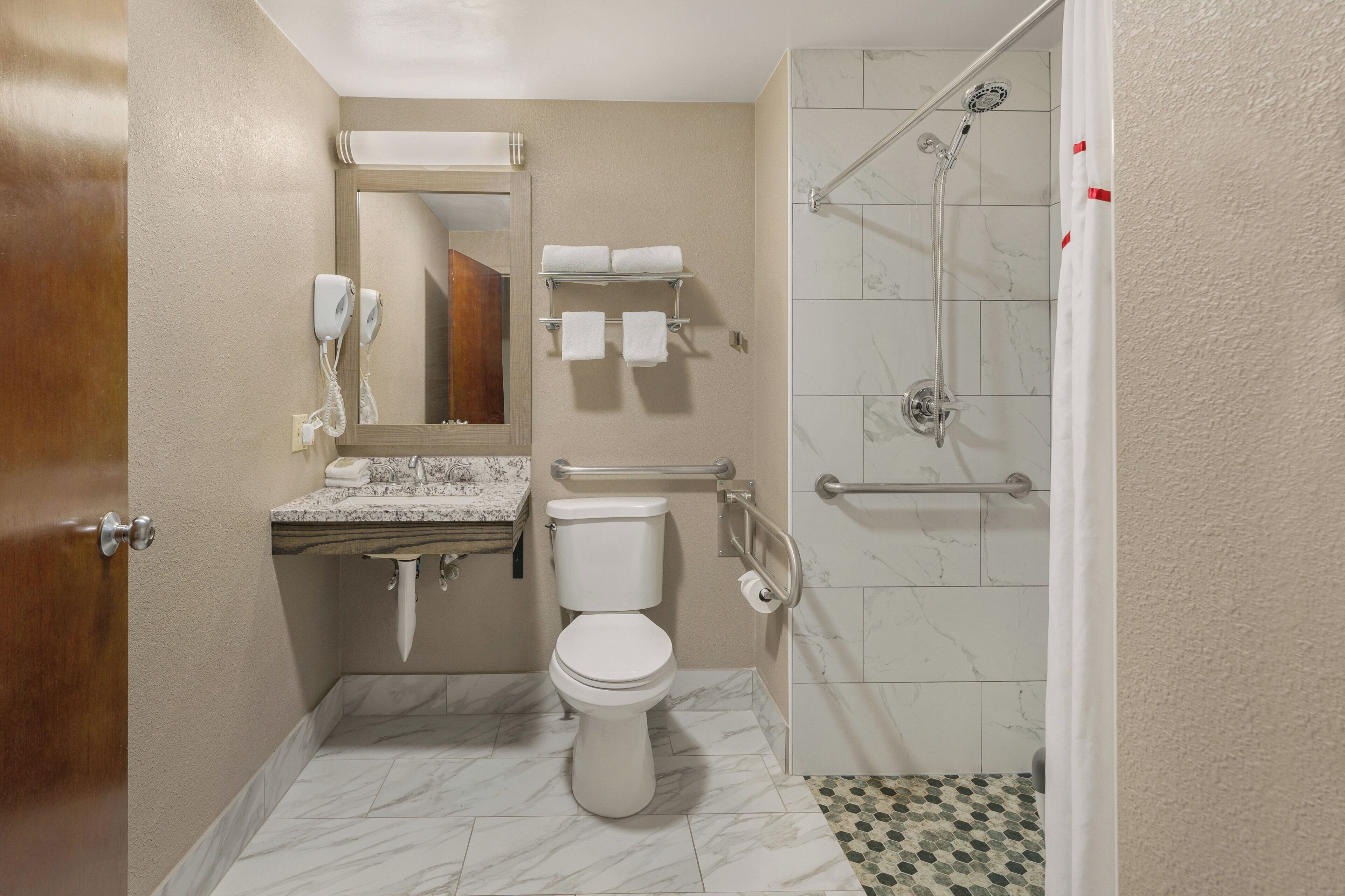 A bathroom with a toilet, sink, mirror, towel rack, and shower.