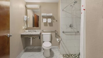 A bathroom with a toilet, sink, mirror, towel rack, and shower.