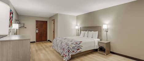 Una camera d'albergo con un letto, lampade ai comodini, una scrivania e una porta.