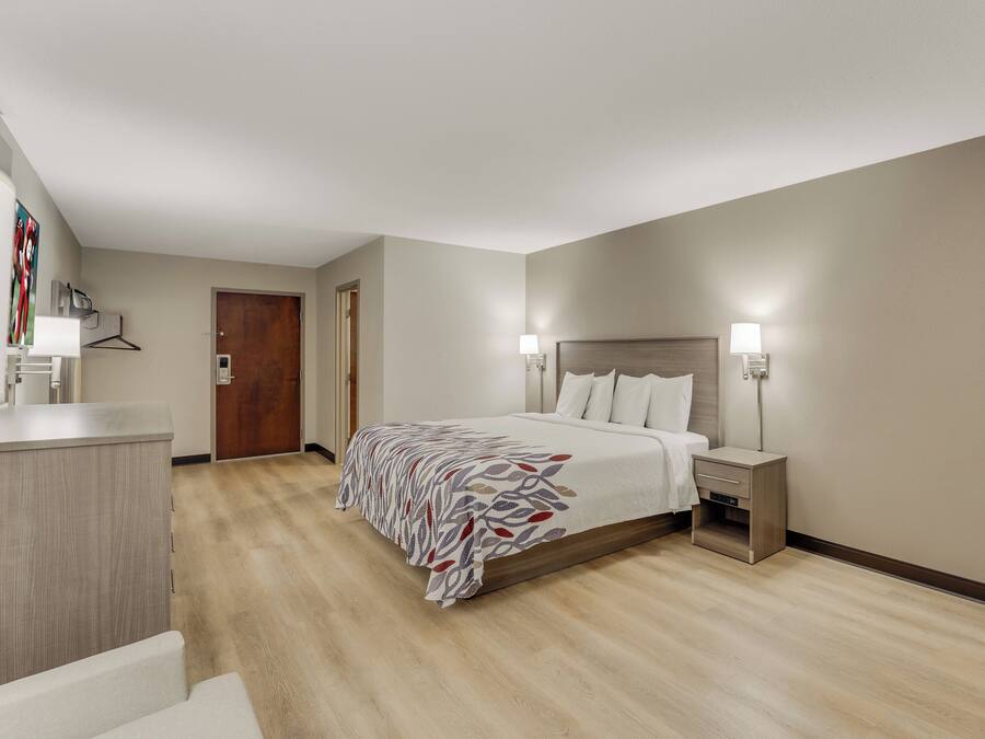 A hotel room with a bed, bedside lamps, a desk, and a door.