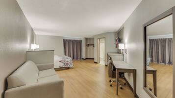 Una camera d'albergo con un letto, una scrivania, una sedia, uno specchio e una lampada.