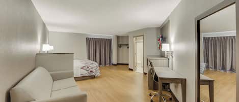 Una habitación de hotel con cama, escritorio, silla, espejo y lámpara.