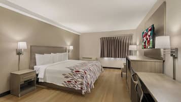 Habitación de hotel con cama, mesitas de noche, escritorio, silla, televisor y ventana con cortinas.