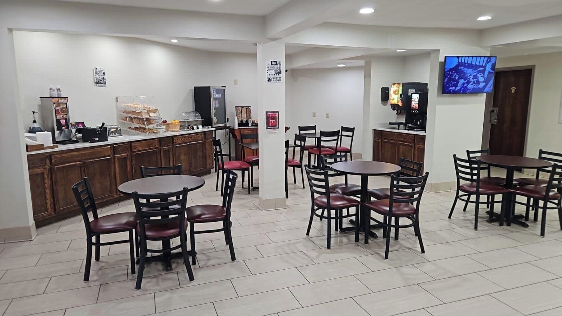 A hotel lobby with a reception desk, seating area, and a TV mounted on the wall.
