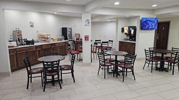 A hotel lobby with a reception desk, seating area, and a TV mounted on the wall.