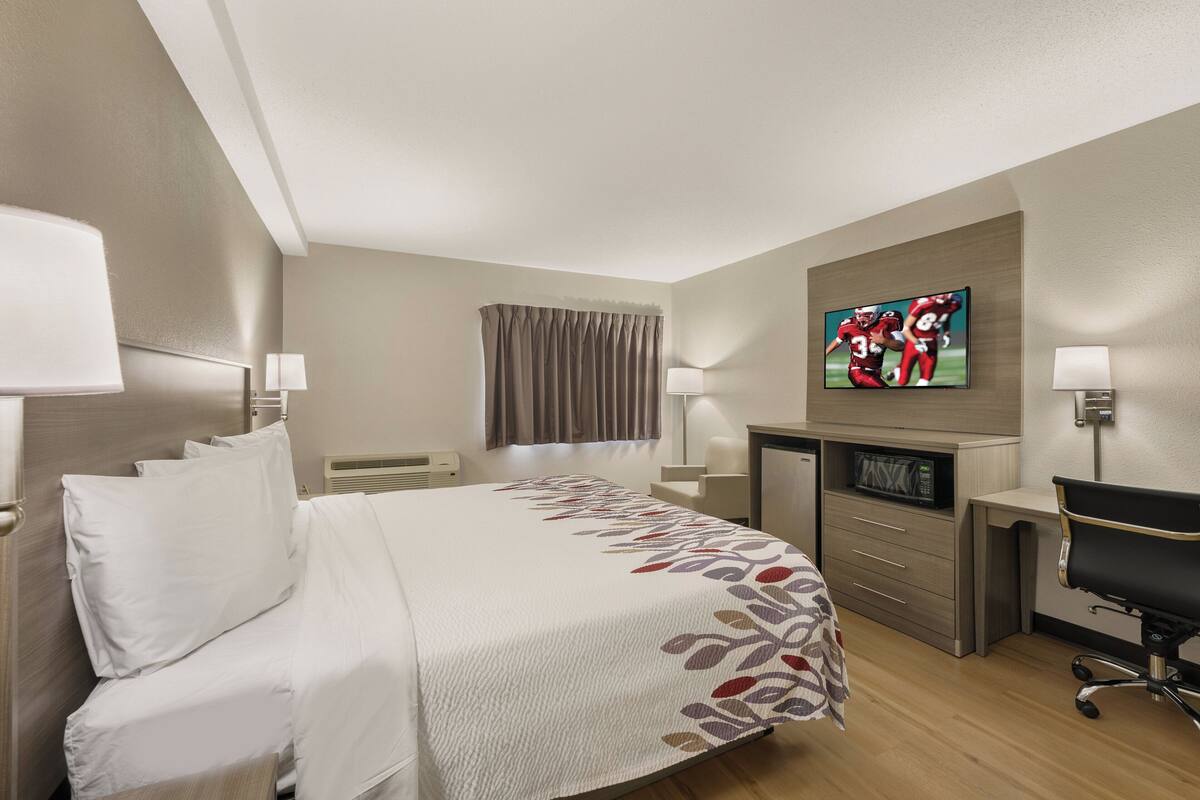 A hotel room with a bed, a desk, a TV, and a microwave.