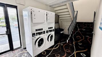 A laundry room with stacked washers and dryers, a staircase, and a patterned floor.