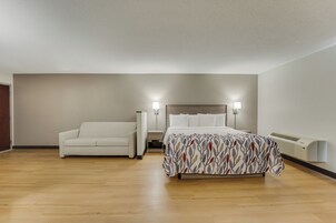 Ein Schlafzimmer mit einem Bett, einem Nachttisch, einer Lampe, einem Sofa und einer Heizung.